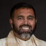 A man with a beard and mustache wearing a white shirt